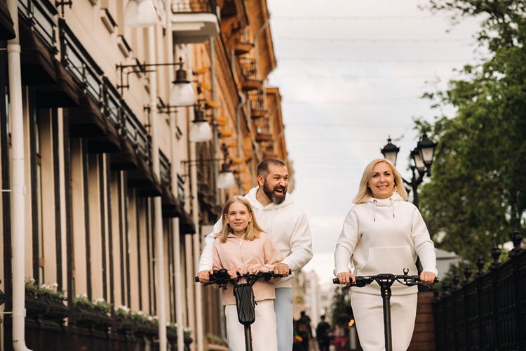 A family in white clothes rides electric scooters in the city.Outdoor activities